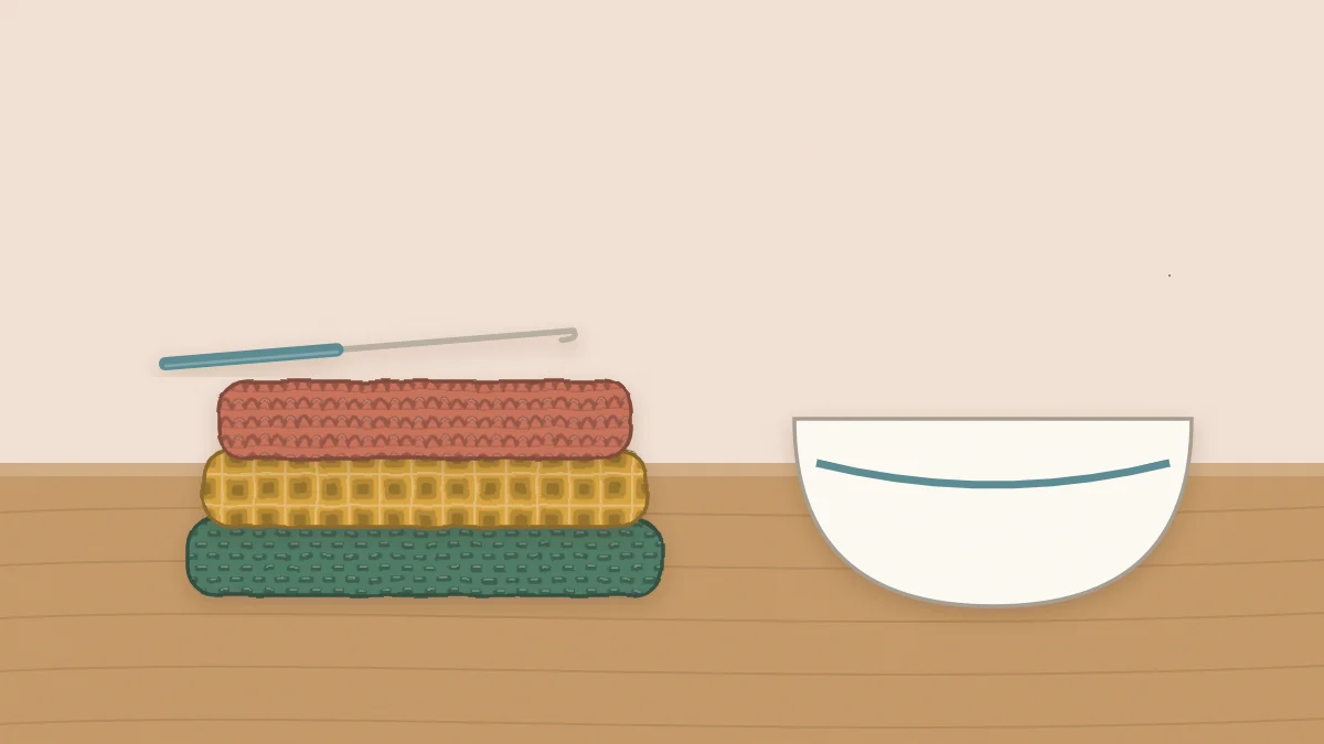 Three folded square crochet dishcloths stacked beside a small bowl near a kitchen sink