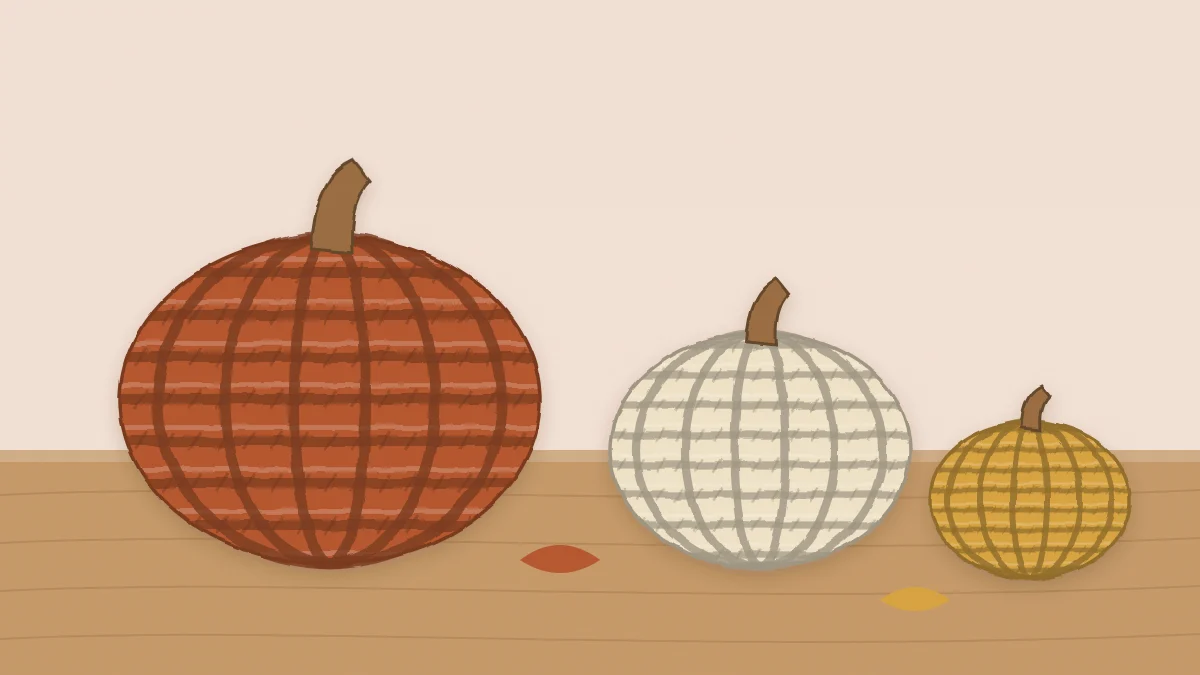 Three crochet pumpkins of different sizes in rust, cream and mustard yarn