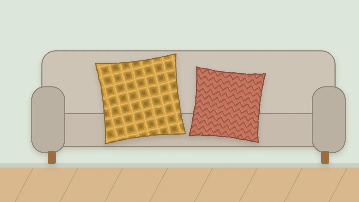 A square textured crochet pillow sitting in the corner of a sofa